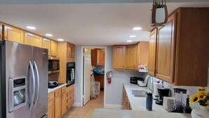 A modern kitchen with wooden cabinets, stainless steel appliances, and a central island. - Spacious 4-bedroom house in tranquil Vero Beach with AC, WiFi (Vero Beach)