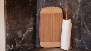 Een keuken met een marmeren spatwand, een houten snijplank, een deegroller en een klein plankje met keukenbenodigdheden.