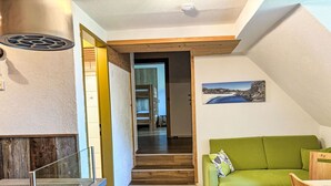 Un interior moderno con un sofá verde, suelo de madera y una escalera que lleva a otra habitación.