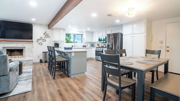 Una cocina moderna con armarios blancos, una isla central y un comedor con sillas y una mesa.