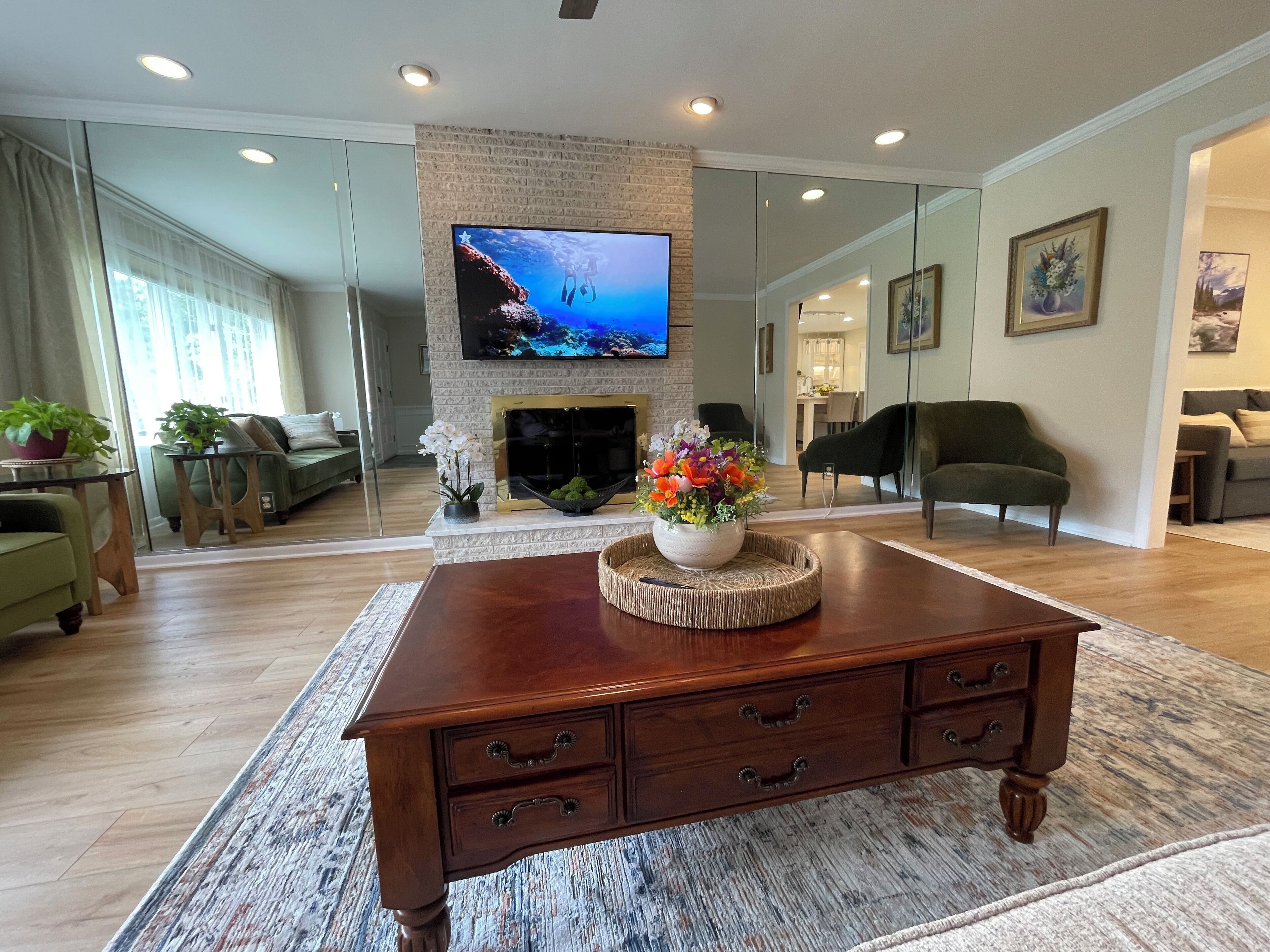 Un salon moderne doté d’une cheminée, d’un téléviseur à écran plat et d’une table basse agrémentée d’un arrangement floral.