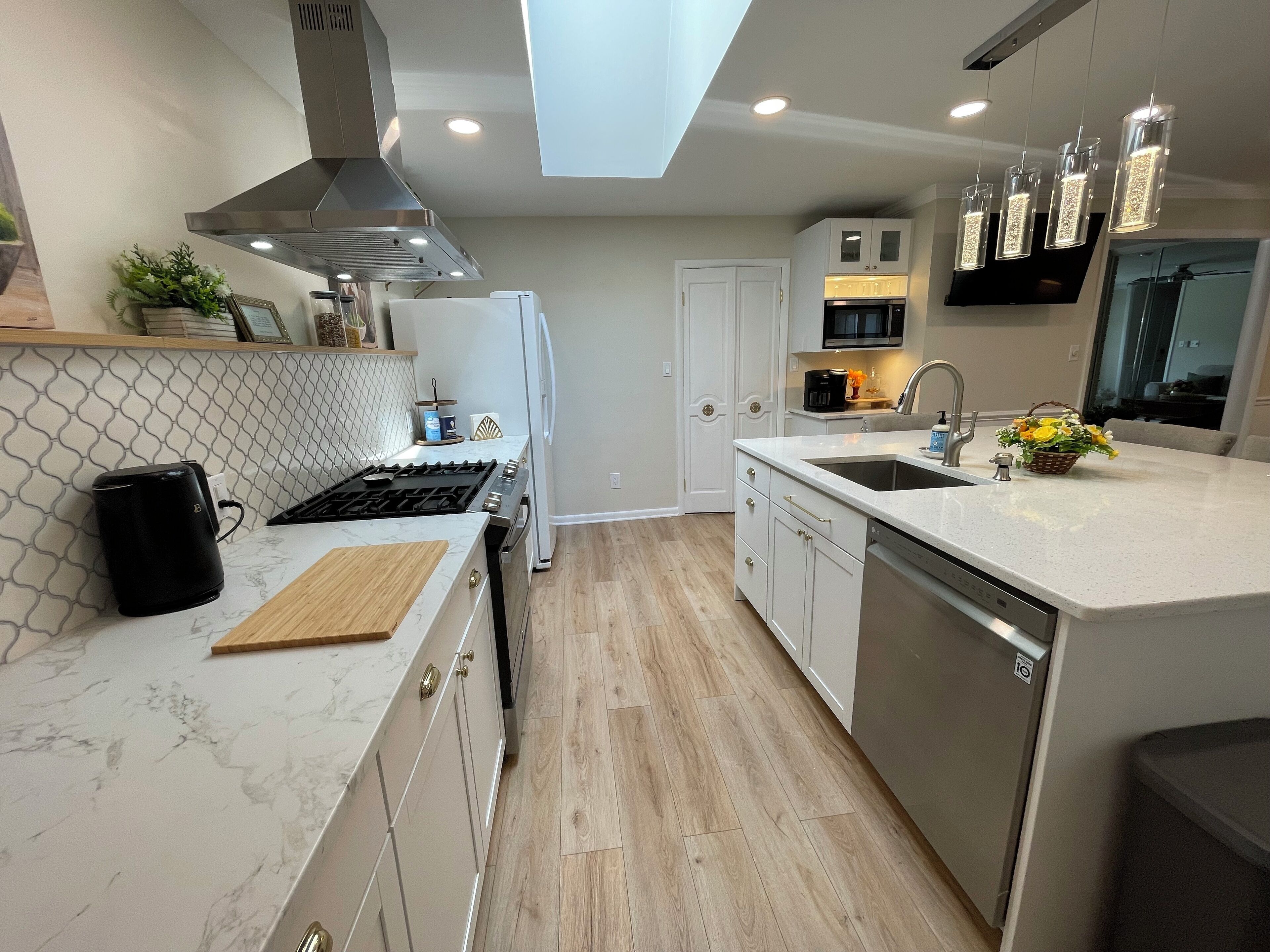 A modern kitchen with a gas stove, white cabinets, a built-in oven, a microwave, and a dishwasher.