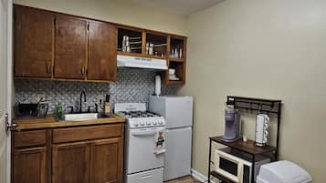 Une cuisine avec des meubles de rangement en bois, une cuisinière, un réfrigérateur, un four à micro-ondes et une poubelle.