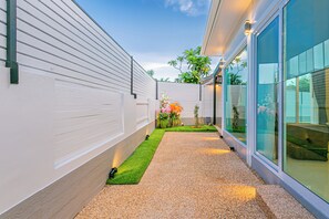 Stroll through the beautifully landscaped grounds, featuring a gravel pathway, lush grass, and a small garden.