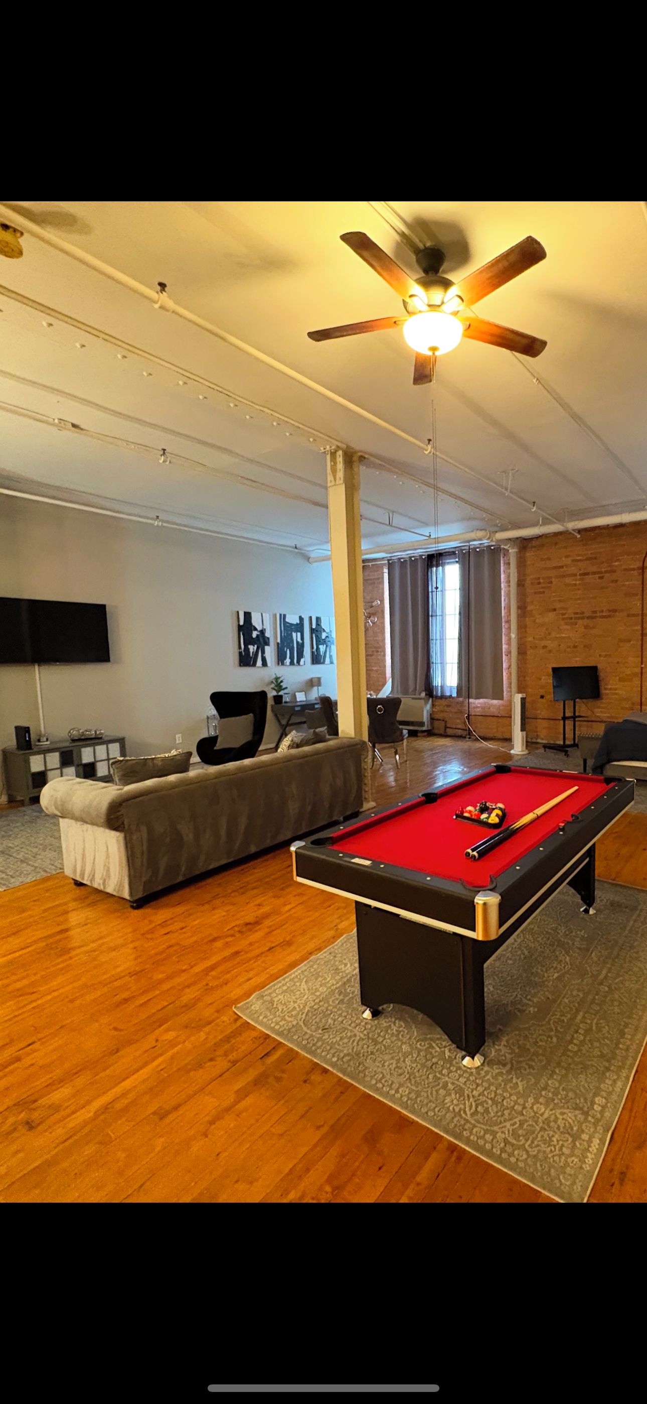 A modern living room with a pool table, a sofa, and a television.