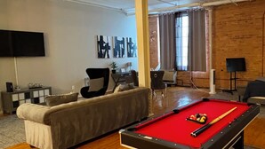 Une pièce spacieuse équipée d’une table de billard, d’un canapé et d’un ventilateur de plafond.