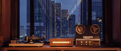 A desk with vintage audio equipment and a cityscape view through large windows.