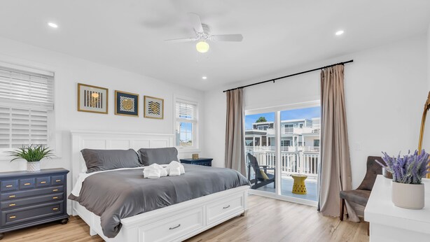 A modern bedroom with a large bed, a ceiling fan, and a view of a balcony. - 3 Stories w/86" TV | Keurig | Pro Cleaned | Garage (Seaside Heights)