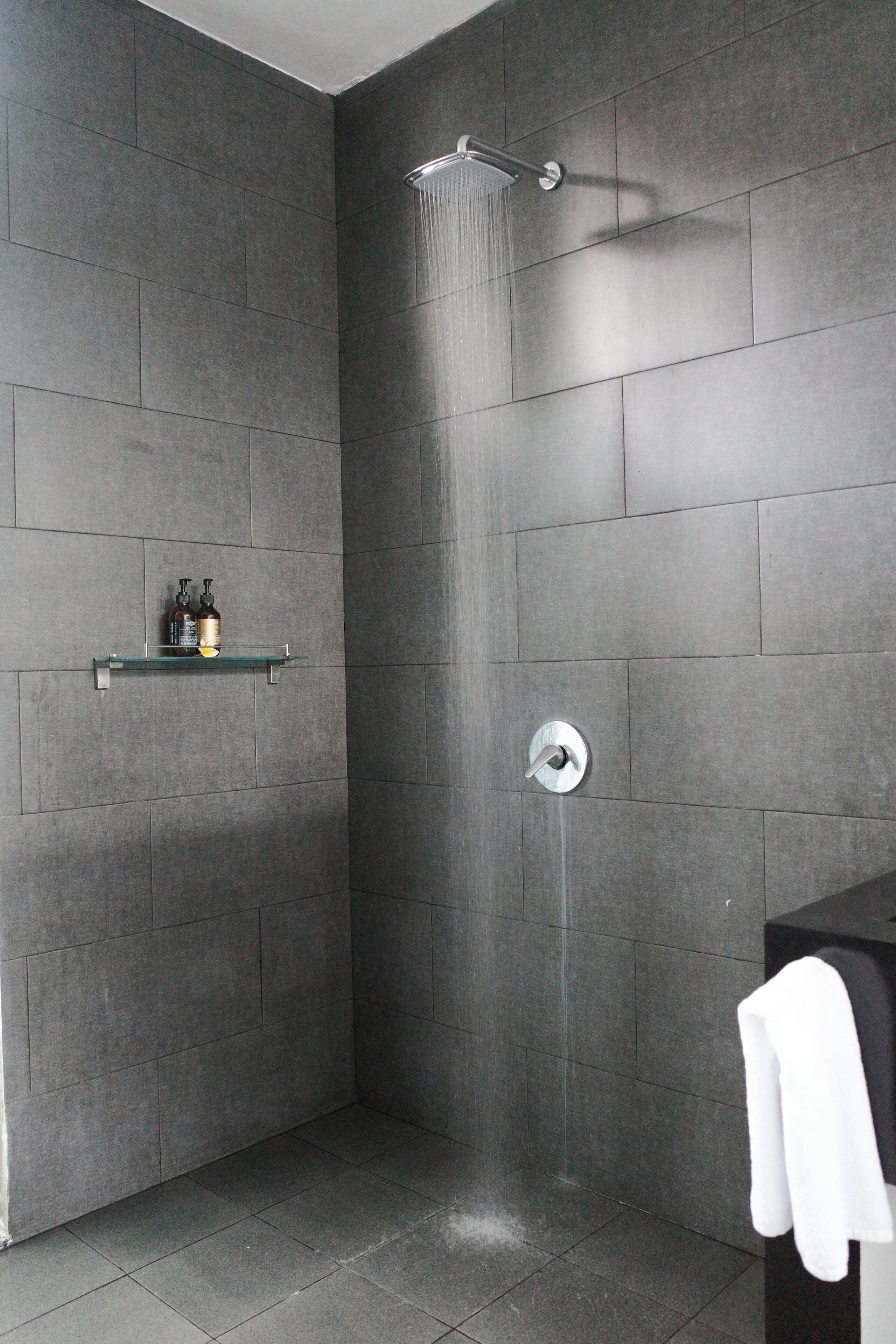 Een moderne badkamer met een douche, een plank met toiletartikelen en een handdoekrek.