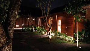 A wooden building with a well-lit entrance and steps leading to a door. - The Riang Villa (Kerobokan)