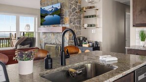 A modern kitchen with a granite countertop, a black faucet, and a stone backsplash.