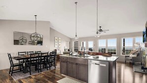 A modern kitchen with a central island, dining area, and large windows.