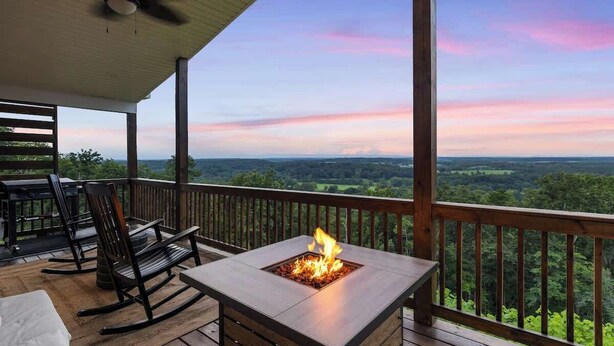 A covered outdoor area with a fire pit, seating, and a view of the landscape.