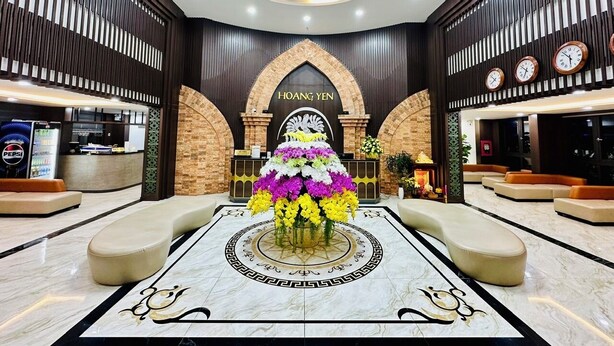 A lobby with a central floral arrangement, a reception desk, and a chandelier. - Hoang Yen Boutique Hotel (Da Nang)