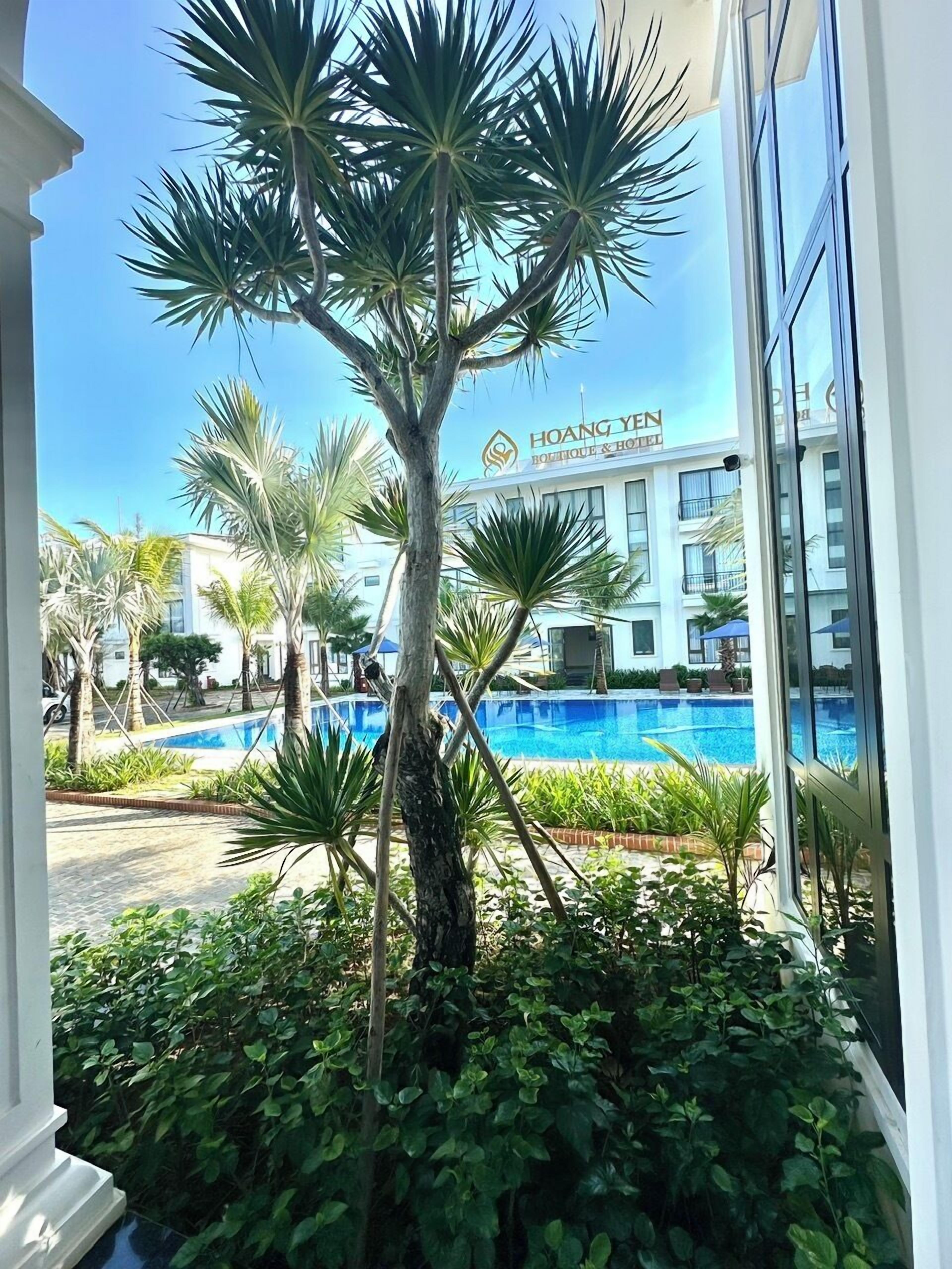 A hotel with a pool, surrounded by palm trees and greenery.