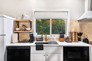 A modern kitchen with a built-in dishwasher, a coffee maker, and a window with a view of greenery.