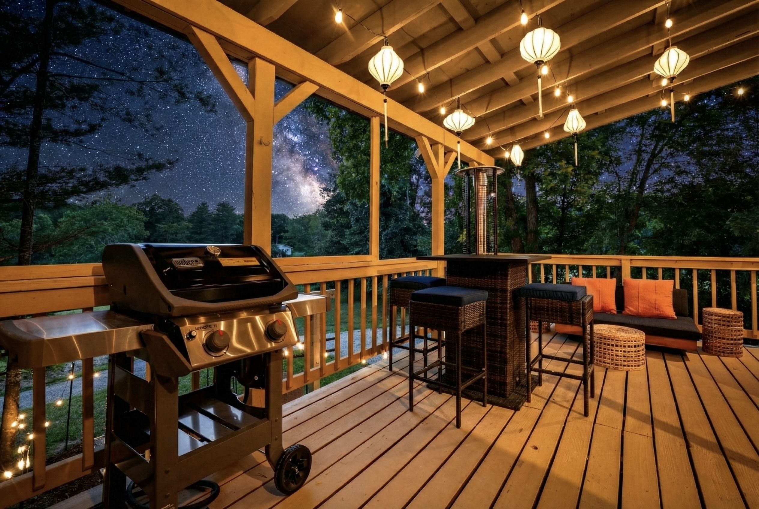 A wooden deck with a grill, bar stools, and a sofa with cushions.