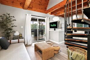 A modern living room with a sofa, a woven bench, a TV displaying 'hulu', and a staircase.