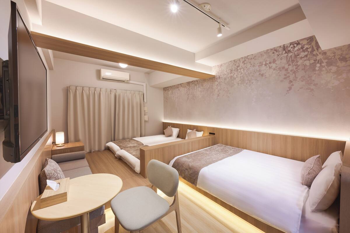 Et hotelværelse med to senge, et fjernsyn, et lille bord og en stol.