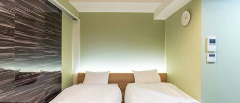 A hotel room with two beds, a wooden headboard, a clock, and a thermostat on the wall.