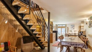 Ein geräumiger Wohnbereich mit einer Holztreppe, einem Esstisch und einer gemütlichen Sitzecke.