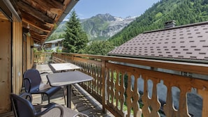 Eine Holzterrasse mit Sitzgelegenheiten und Blick auf die Berge.