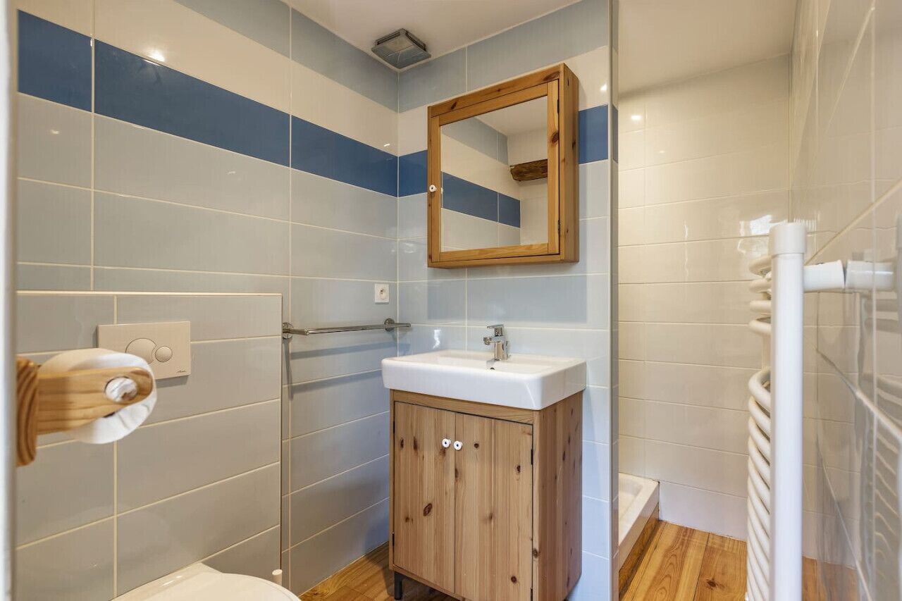 Un baño con un armario de madera, un lavamanos blanco y un espejo.