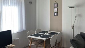 En matplats med ett bord, stolar, en tv och en golvlampa.