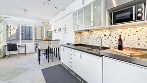 A modern kitchen with white cabinets, a stainless steel microwave, and a tiled backsplash. - Solaga - Martinez Virel (Málaga)