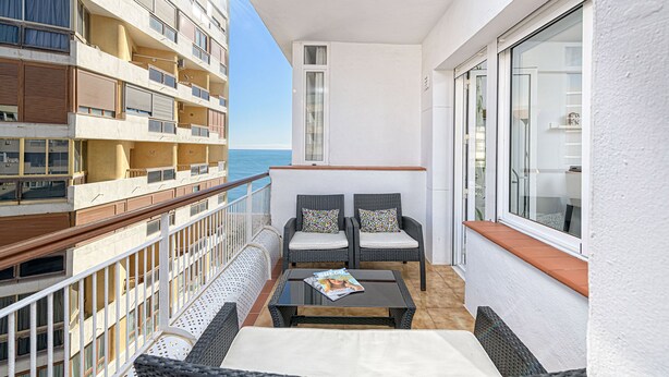 A balcony with wicker furniture, a magazine on the table, and a view of the sea. - Solaga - Martinez Virel (Málaga)