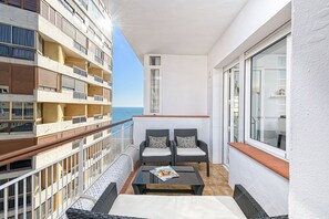 Ein Balkon mit Korbmöbeln, einer Zeitschrift auf dem Tisch und Blick aufs Meer.