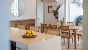 A dining area with a wooden table and chairs, a bowl of lemons on the table, and a large mirror on the wall.