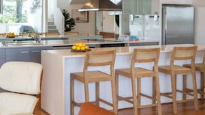 A modern kitchen with a central island, stainless steel appliances, and wooden bar stools.