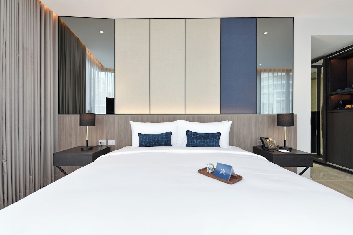 Une chambre d’hôtel avec un grand lit, deux tables de chevet, un miroir et une vue sur la ville.