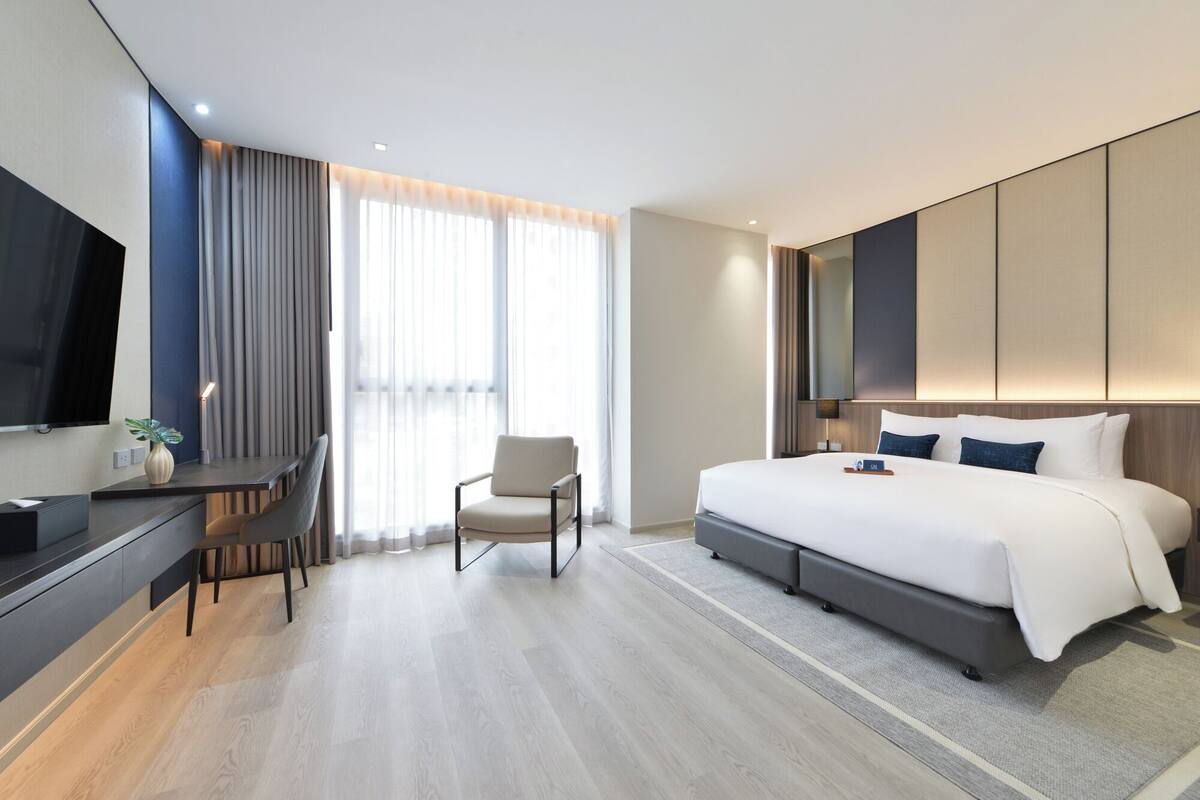 Une chambre d’hôtel moderne équipée d’un grand lit, d’un bureau, d’une chaise et d’un téléviseur.