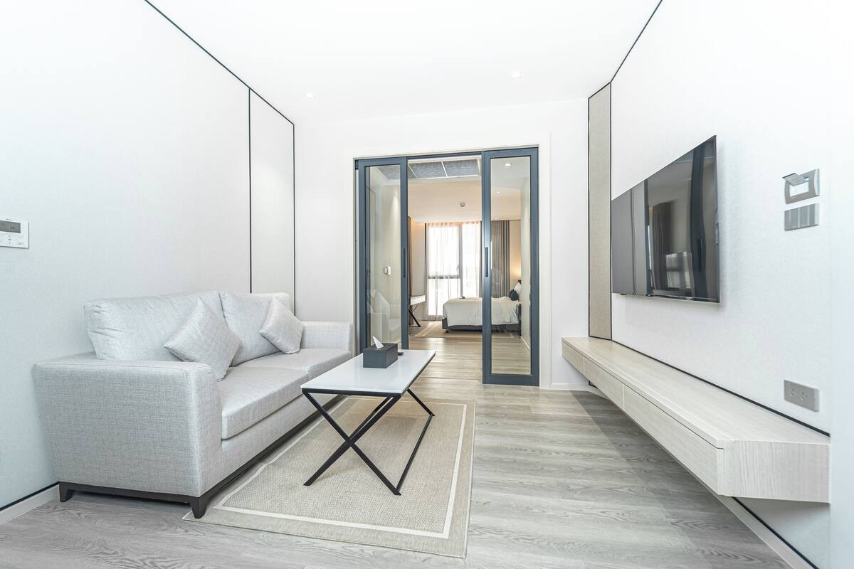 Un salon moderne avec un canapé gris, une table basse et un téléviseur à écran plat fixé au mur.
