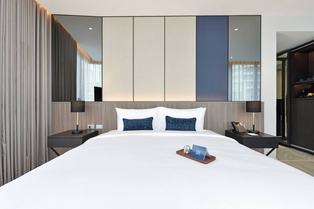 Une chambre d’hôtel avec un grand lit, deux tables de chevet, un miroir et une vue sur la ville.