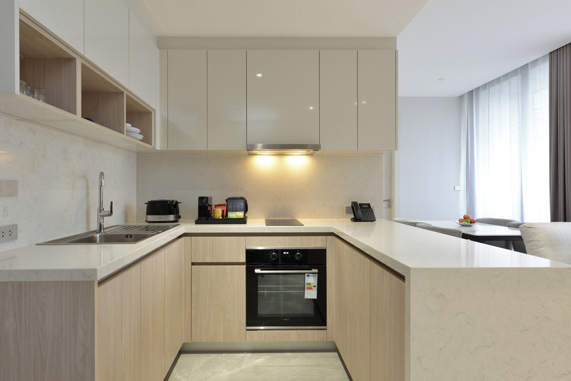 A modern kitchen with a built-in oven, a coffee machine, and a phone on the counter.