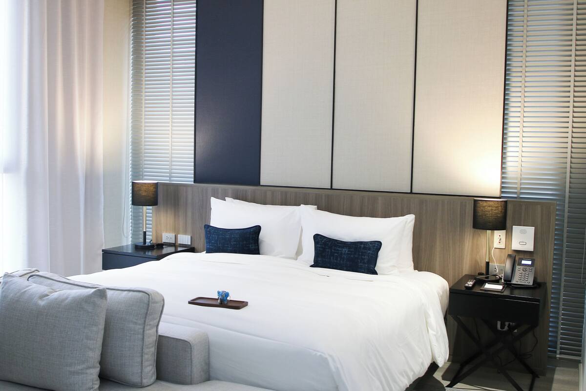 Une chambre d’hôtel moderne avec un grand lit, deux tables de chevet, un bureau et une chaise.