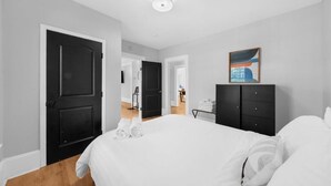 A hotel room with a bed, a wardrobe, a desk, and a painting on the wall.