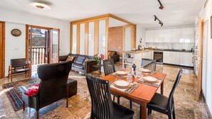 A spacious living area with a dining table set for four, a sofa, and a kitchen with white cabinets. - Solaga - Mary (Málaga)