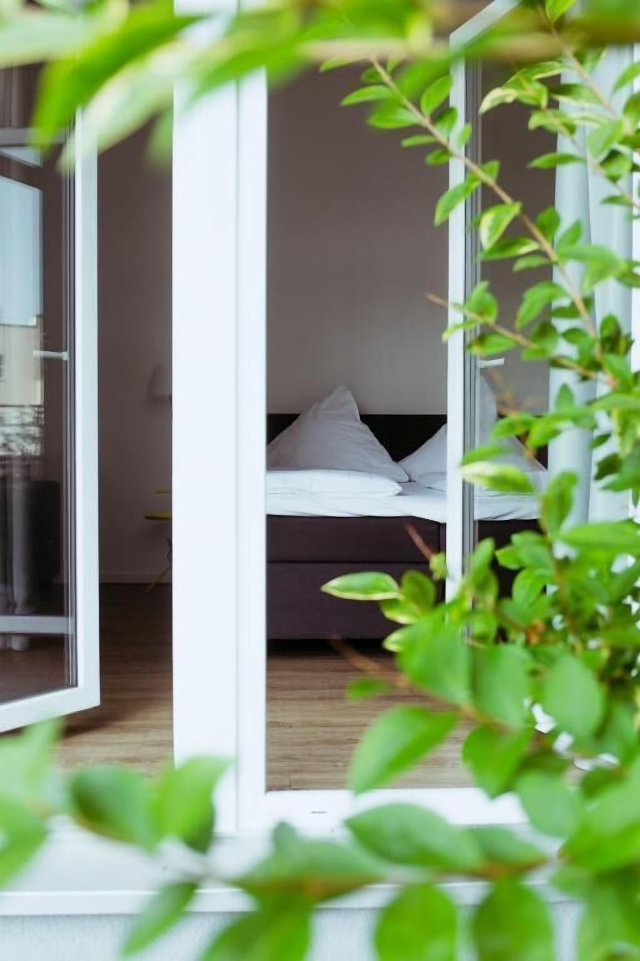 A bedroom with a bed, a window, and a view of another room.