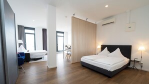A modern hotel room with a large bed, a desk, and a chair. - Das Loft Apartments (Aachen)