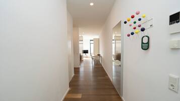 Un couloir doté d’un plancher en bois, de murs blancs et d’un coin repas situé au fond.