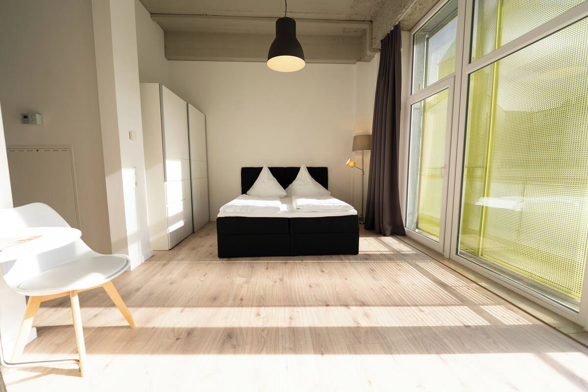 A modern bedroom with a large bed, a desk, and a chair.