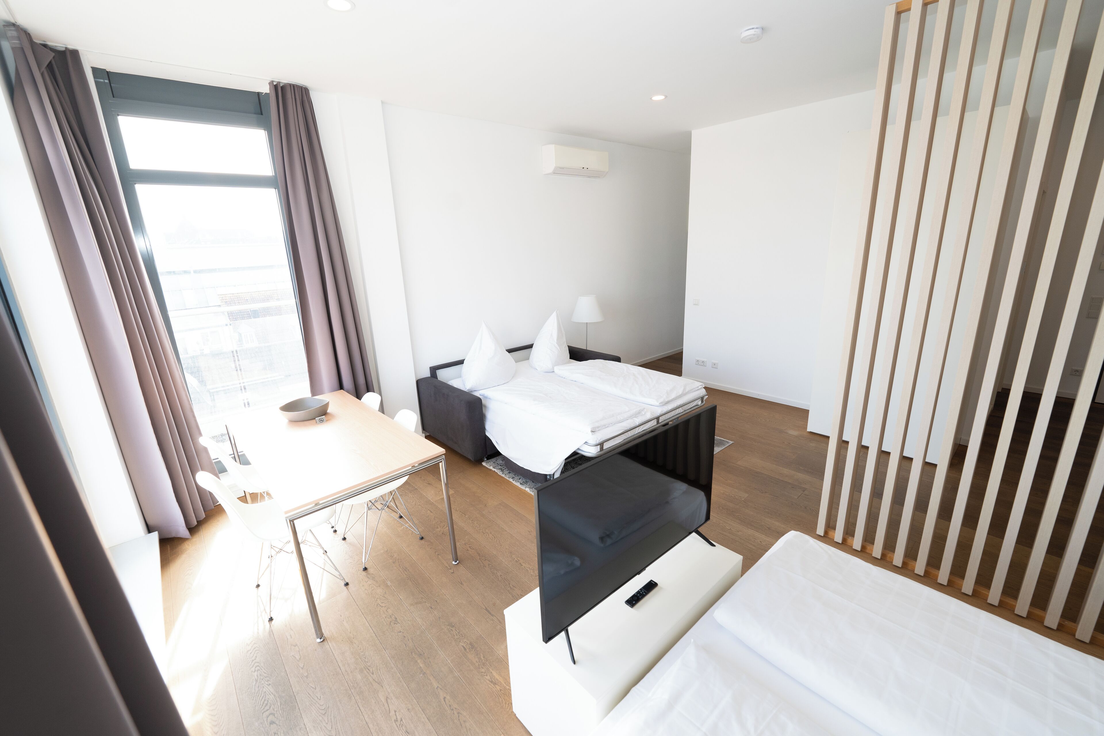 A modern hotel room with a bed, a desk, and a chair.