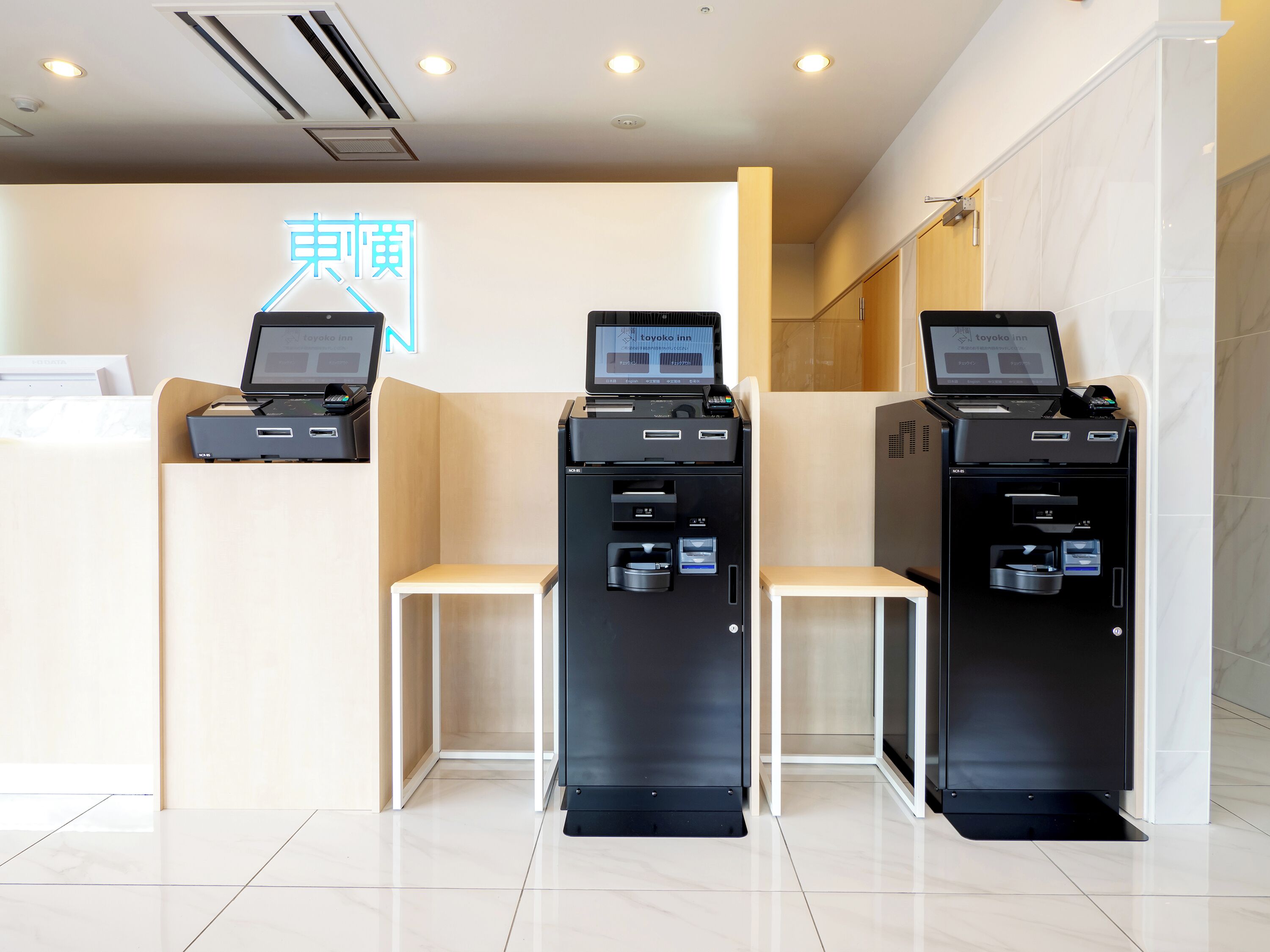 A reception area with three black self-service kiosks, a wooden bench, and a sign with Chinese characters.