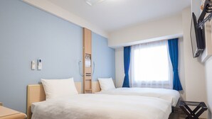 Een hotelkamer met twee bedden, een houten garderobe, een nachtkastje, een aan de muur bevestigde televisie en een raam met blauwe gordijnen.