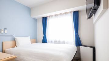 Una habitación de hotel con cama, escritorio, televisor y calefacción.