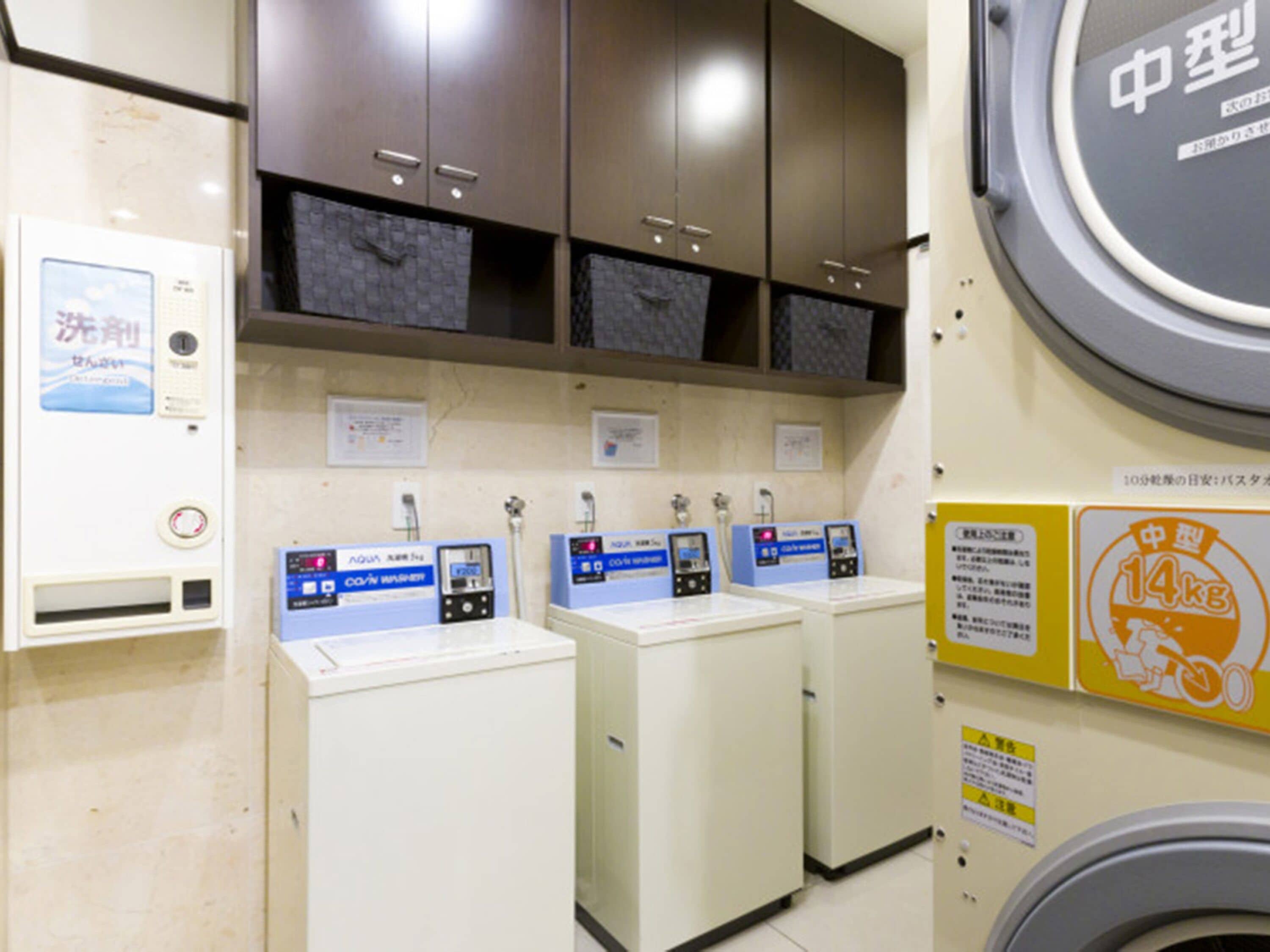 Une buanderie équipée de trois machines à laver, d’un sèche-linge et d’un chauffe-eau.